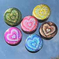 a group of colorful heart shaped buttons on a glass surface