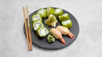 japanese sushi on a black plate with chopsticks