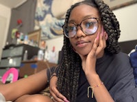 a young black woman wearing glasses laying on a bed