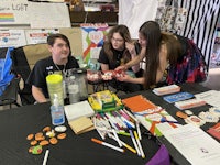 a group of people at a table with a table full of supplies