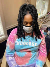 a woman wearing a tie dye shirt sitting in a chair