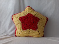 a red and yellow crocheted star pillow