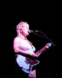 a woman playing a guitar in front of a microphone