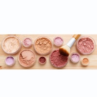 various makeup powders and brushes on a wooden table
