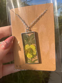 a person holding a necklace with a yellow flower on it