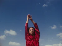 a woman in a red shirt with her arms raised in the air