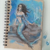 a sketch of a mermaid sitting on a rock
