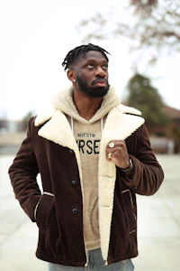 a black man wearing a brown sherpa jacket and hoodie
