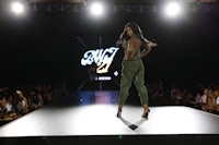 a woman is walking down the runway at a fashion show