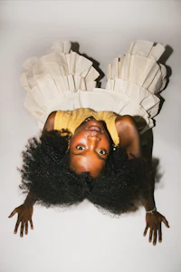 a black woman in a white dress laying on her stomach