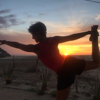 a woman doing a yoga pose at sunset