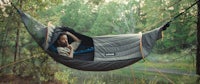a man sleeping in a hammock in the woods