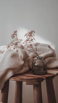 a wooden table with a vase and a blanket on it
