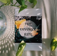 the divorce rite book on a table next to a plant