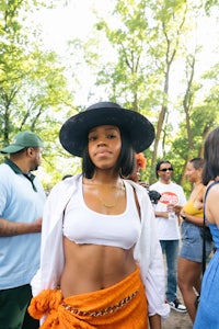 a woman in an orange top and hat standing in a crowd
