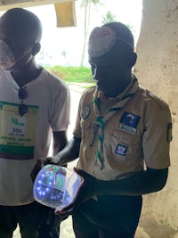 two scouts holding a device with a light on it
