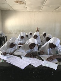 a group of girls sitting at a table with papers