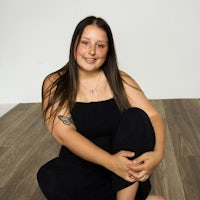a woman sitting on a wooden floor with tattoos