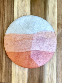 an orange and pink coaster on a wooden cutting board