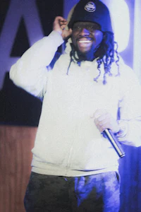 a man with dreadlocks smiles while holding a microphone