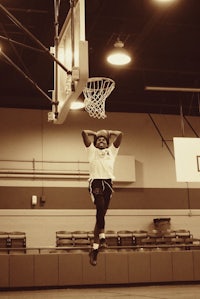 a man dunks a basketball in a gym
