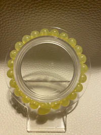 a clear glass holder with yellow beads on it