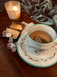 a tea cup on a tray next to a candle