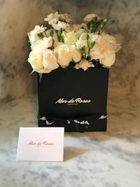 white roses in a black box with a card