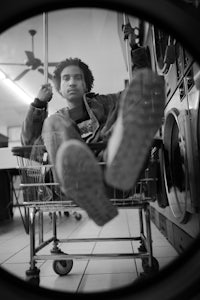 a black and white photo of a man sitting in a laundry cart
