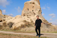 a man is standing in front of a rock formation
