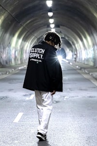 a man walking through a tunnel with a black jacket