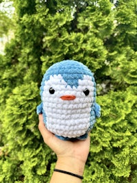 a crocheted penguin is being held in a person's hand