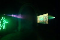 a neon projection of a man playing a game in a dark room