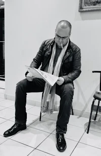 a man sitting on a chair reading a newspaper