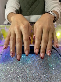 a woman's hands with red and white nails on a table