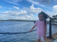 a little girl standing on a railing near the water