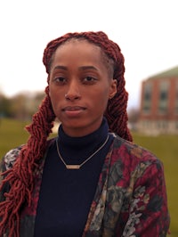 a woman with red dreadlocks standing in front of a building