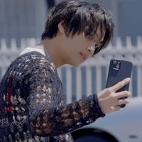a young man holding a cell phone while walking down the street