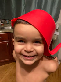 a young boy wearing a red hat in a kitchen