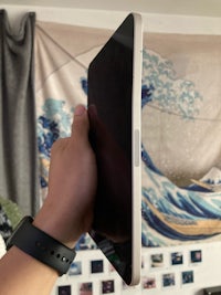 a person holding up an ipad in front of a wall