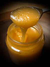 a spoon is dripping honey into a jar