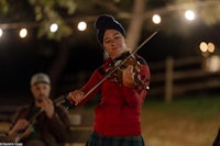 a woman playing a violin in front of a group of people