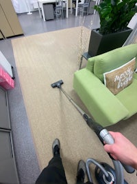 a person using a vacuum to clean a green couch
