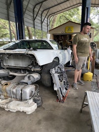 a man standing next to a car in a garage