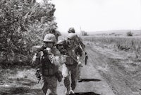 a group of soldiers walking down a dirt road