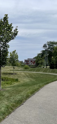 a paved path leading to a grassy field and a house