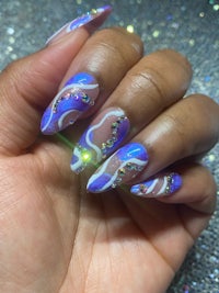 a woman's hand with purple and blue nail art