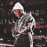 a man in a hoodie is standing in front of a fire
