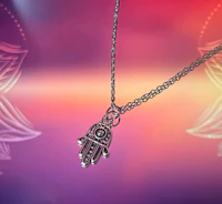 a silver hamsa necklace on a purple background