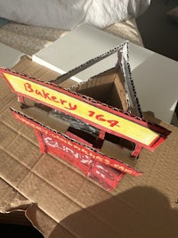 a cardboard model of a restaurant sign on top of a bed